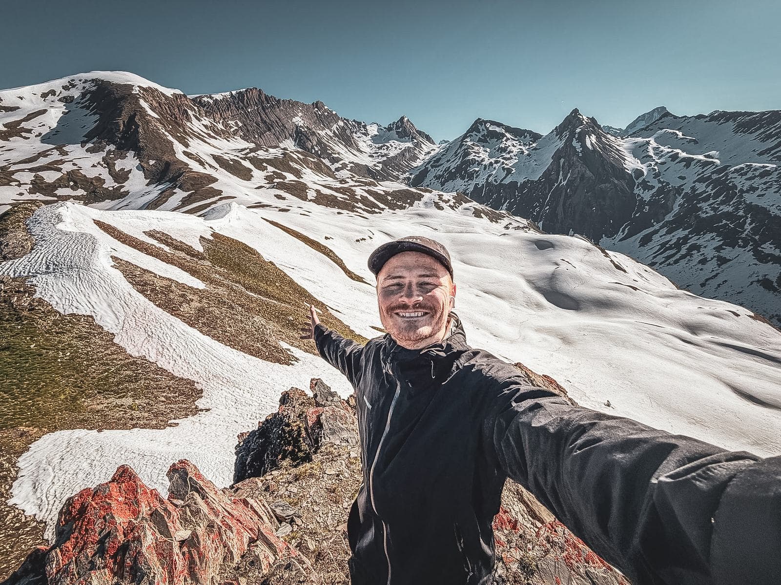Pierre Biege auf einem verschneiten Grat, Arme ausgebreitet